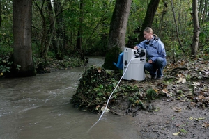 Une femme surveille la qualité de l'eau d'une rivière dans une forêt