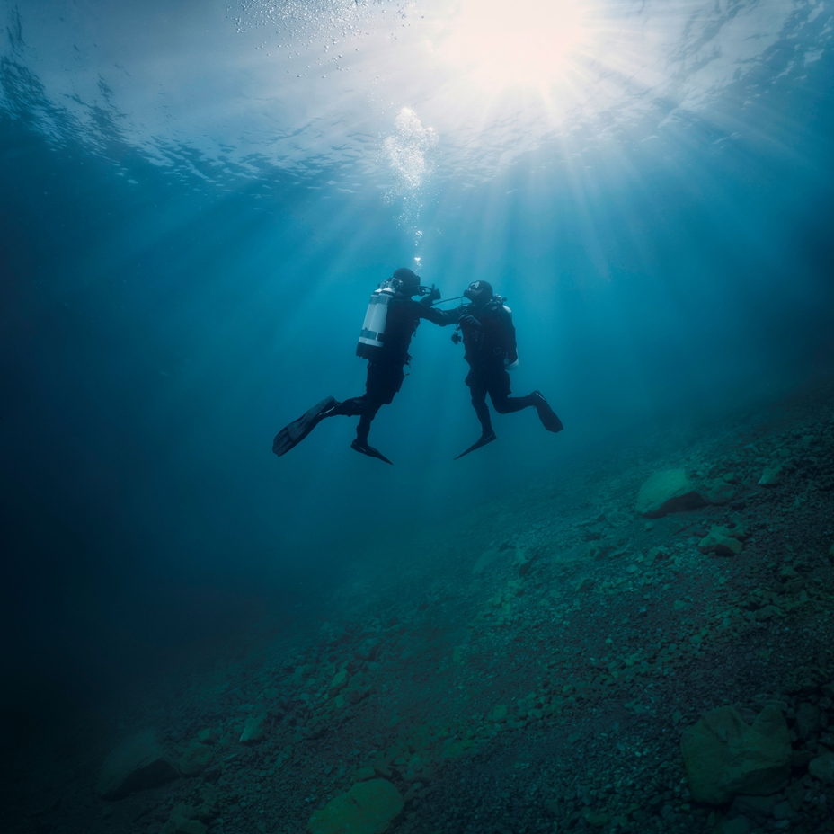 Scène sous-marine : un plongeur soutient un autre plongeur qui a des problèmes d'alimentation en oxygène.