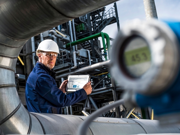 Engineer working on an industrial tablet in a refinery environment.