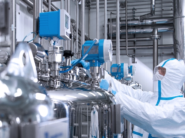 Ingénieur en combinaison hygiénique manipulant un appareil dans un environnement des sciences de la vie.