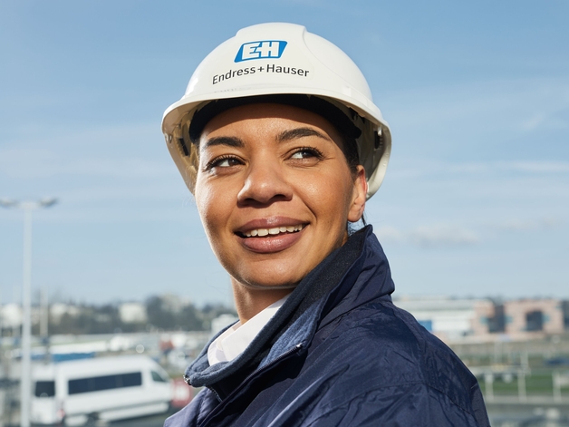 Femme ingénieur avec un casque blanc devant un ciel bleu.